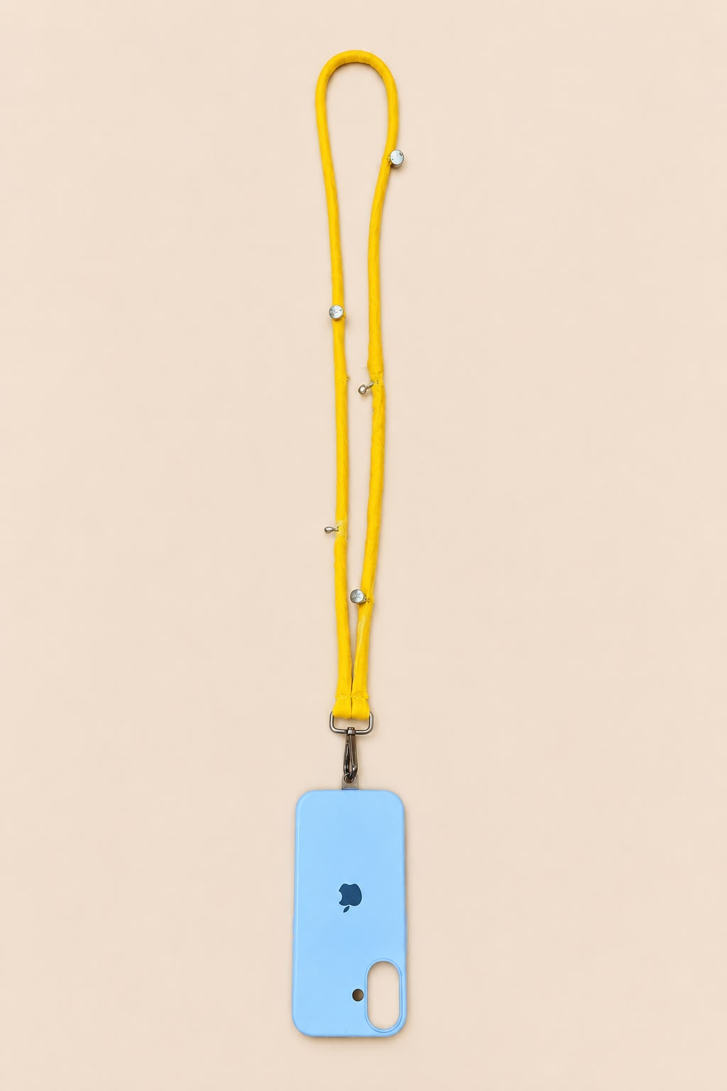 A light blue phone case with a bright yellow lanyard strap featuring small silver beads, displayed on a solid pale peach background.