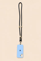 A light blue phone case with a black lanyard strap and gold-tone hardware, shown flat against a solid pale beige background.